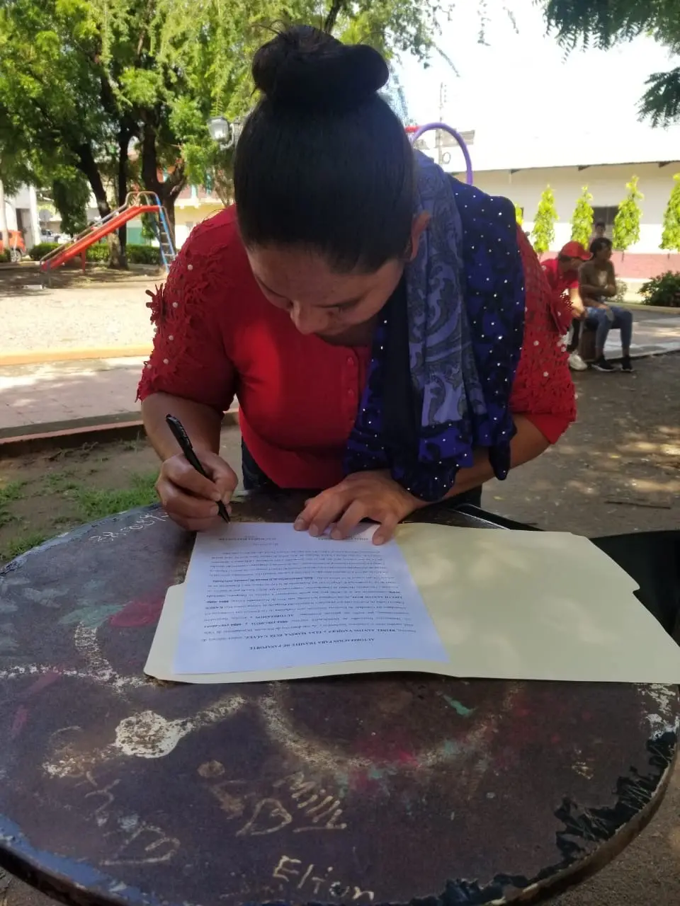 Clienta hondureña firma una autorización legal en Honduras durante un trámite acompañado por Abogados Catrachos USA.