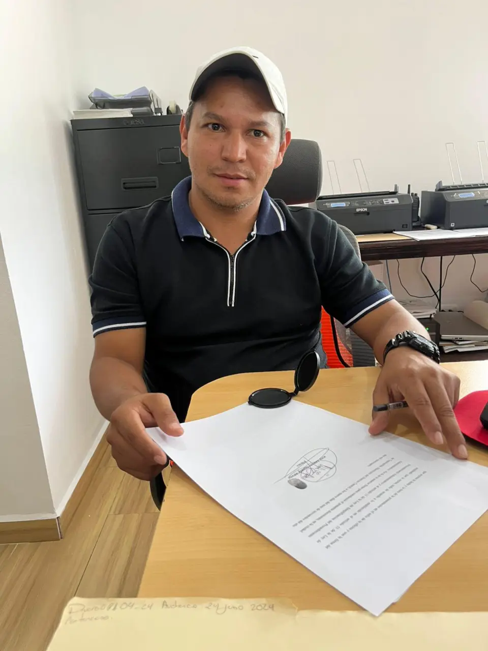 Cliente muestra un documento firmado en una oficina durante un trámite con Abogados Catrachos USA.