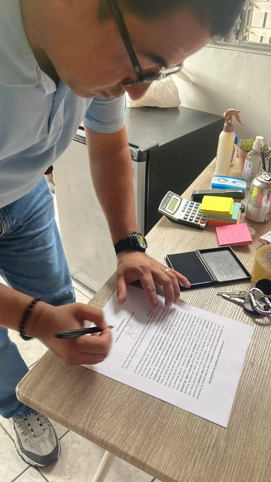 Cliente firma un documento legal sobre una mesa de oficina durante una gestión de Abogados Catrachos USA.