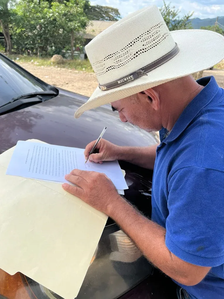 Cliente hondureño firma una carta poder preparada por Abogados Catrachos USA para un trámite legal válido desde Estados Unidos hacia Honduras.