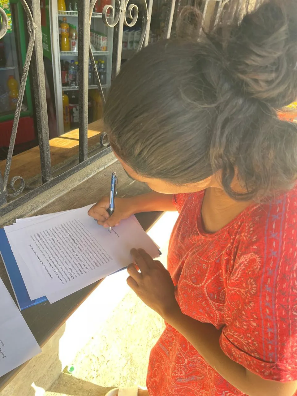 Joven hondureña firma documentos de Abogados Catrachos USA para trámites legales de menores y autorizaciones familiares entre Honduras y Estados Unidos.